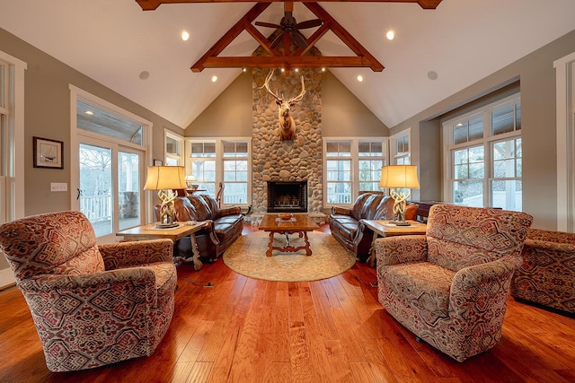 living room featuring high vaulted ceiling, wood-type flooring, a fireplace, and a healthy amount of sunlight