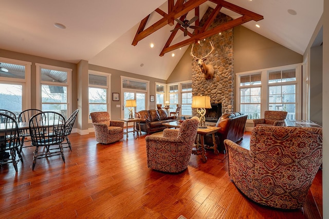 living room featuring high vaulted ceiling, a stone fireplace, beamed ceiling, and hardwood / wood-style flooring