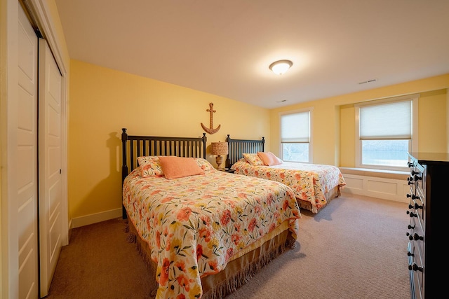 carpeted bedroom with a closet, visible vents, and a decorative wall