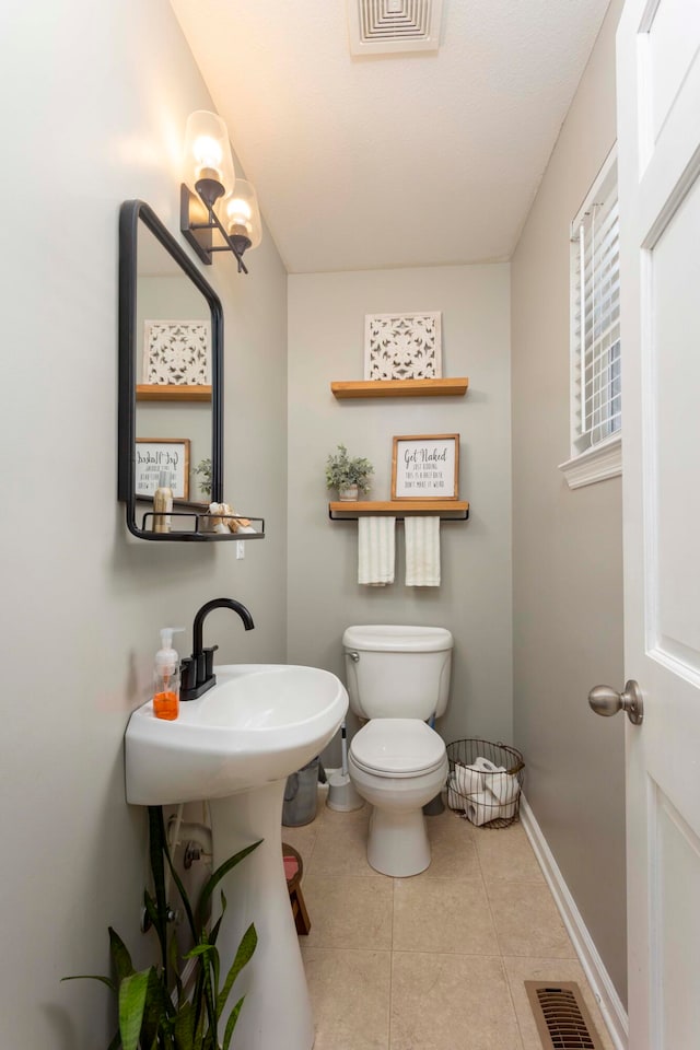 bathroom featuring tile patterned floors, toilet, and a chandelier