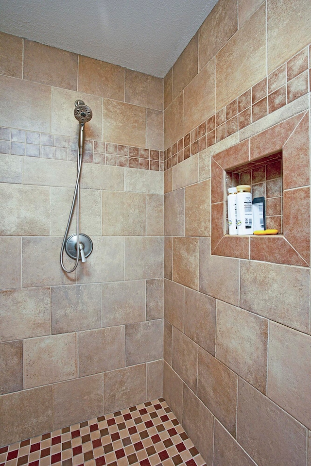 bathroom with tiled shower and a textured ceiling