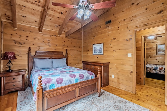 bedroom with ceiling fan, light hardwood / wood-style flooring, and wood walls