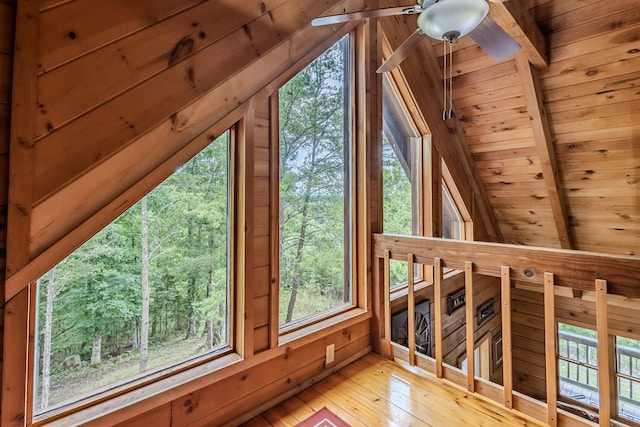 interior space featuring wood ceiling, ceiling fan, wooden walls, vaulted ceiling with beams, and light hardwood / wood-style floors