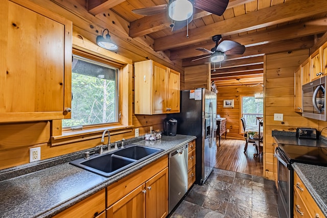 kitchen with stainless steel appliances, dark wood-type flooring, sink, beam ceiling, and wood walls