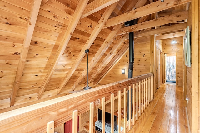 corridor with lofted ceiling with beams, wood walls, wooden ceiling, and hardwood / wood-style flooring