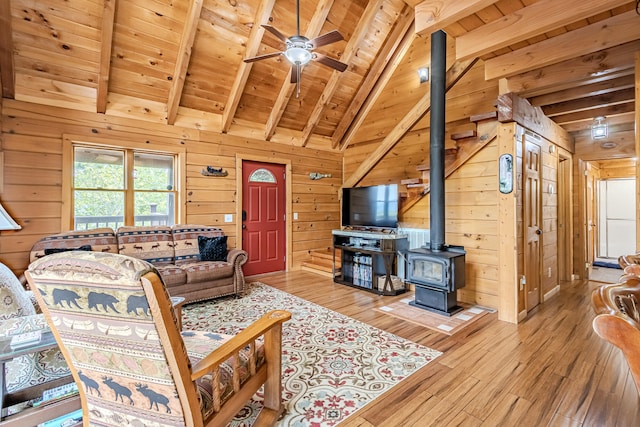 living room featuring a wood stove, wooden walls, light hardwood / wood-style flooring, and wood ceiling