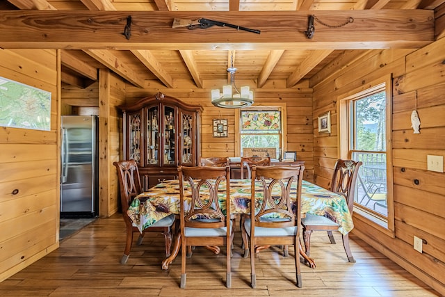 dining room featuring wood ceiling, wood-type flooring, an inviting chandelier, beamed ceiling, and wood walls