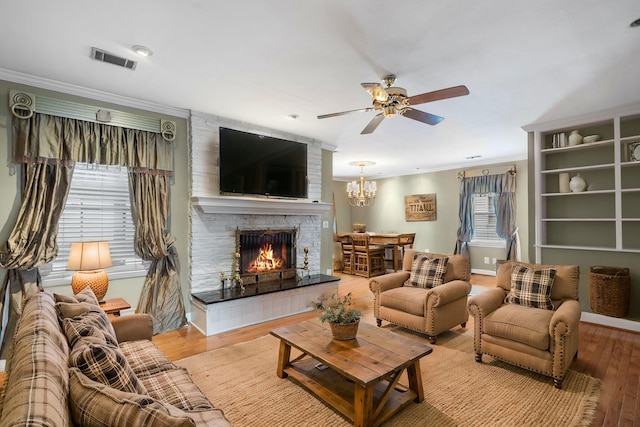 living room with light hardwood / wood-style floors, ceiling fan, ornamental molding, and a tiled fireplace