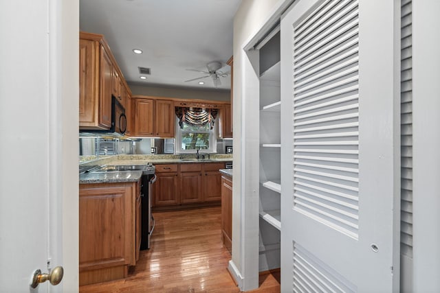 kitchen with light stone countertops, ceiling fan, sink, light hardwood / wood-style floors, and black appliances