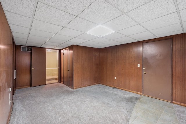 basement featuring a paneled ceiling and wood walls