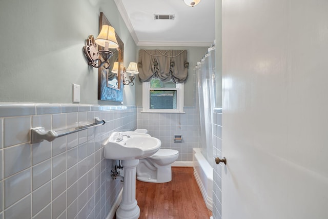 bathroom with hardwood / wood-style floors, shower / bath combination with curtain, toilet, tile walls, and ornamental molding