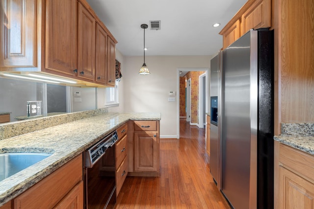 kitchen featuring pendant lighting, dishwasher, kitchen peninsula, light hardwood / wood-style flooring, and stainless steel fridge with ice dispenser