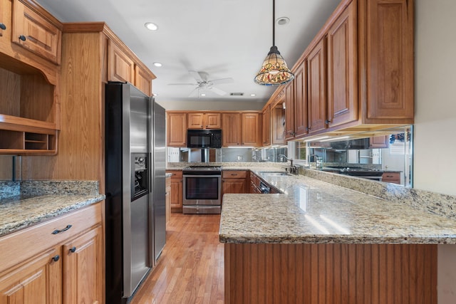 kitchen featuring sink, stainless steel appliances, light hardwood / wood-style flooring, kitchen peninsula, and decorative light fixtures