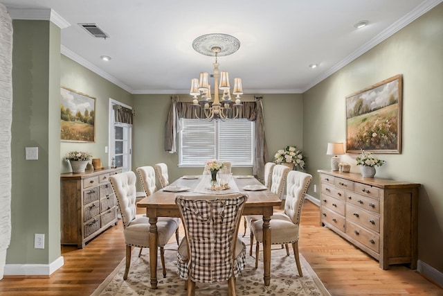 dining room with a chandelier, light wood-type flooring, and ornamental molding