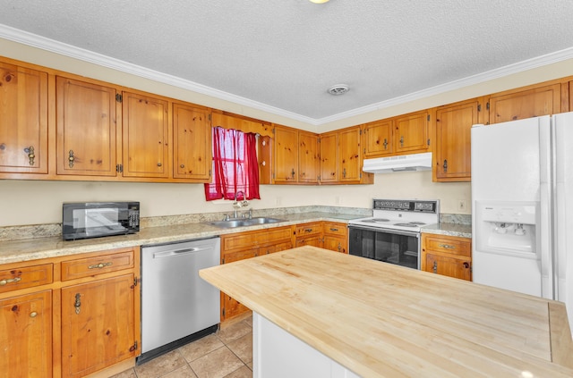 kitchen featuring butcher block counters, brown cabinetry, a sink, white appliances, and under cabinet range hood