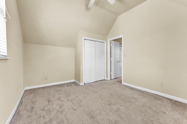 unfurnished bedroom featuring lofted ceiling, baseboards, a closet, and light colored carpet