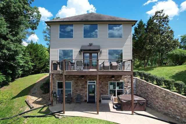 rear view of house with a balcony, a yard, a patio, and french doors