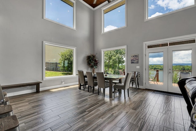 dining area with a high ceiling, french doors, plenty of natural light, and wood-type flooring