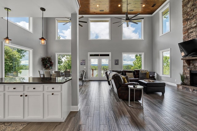 living room featuring a healthy amount of sunlight, a towering ceiling, and wood ceiling