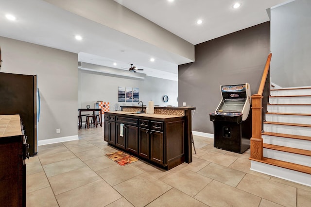 kitchen featuring stainless steel refrigerator, ceiling fan, sink, a kitchen breakfast bar, and a center island with sink