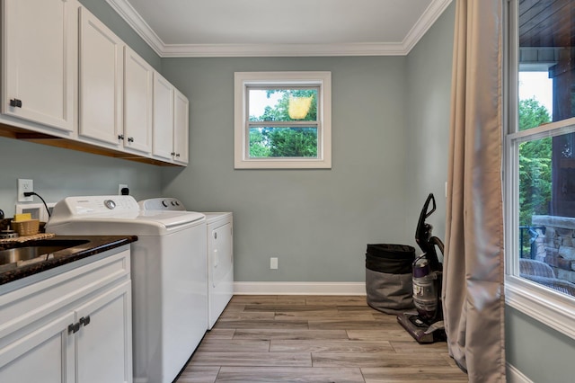 clothes washing area featuring washing machine and dryer, ornamental molding, cabinets, and light wood-type flooring