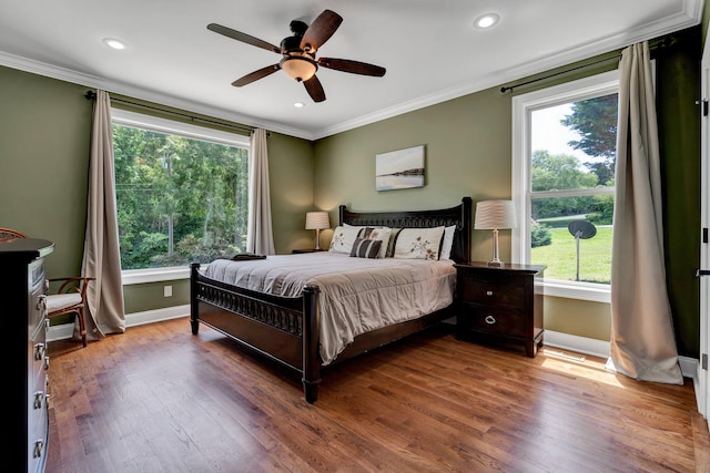 bedroom with hardwood / wood-style flooring, ceiling fan, crown molding, and multiple windows