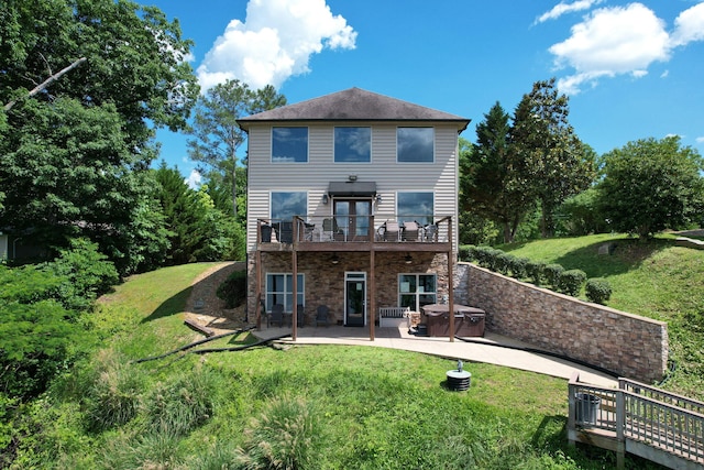 rear view of property with a patio area, a yard, a balcony, and a hot tub