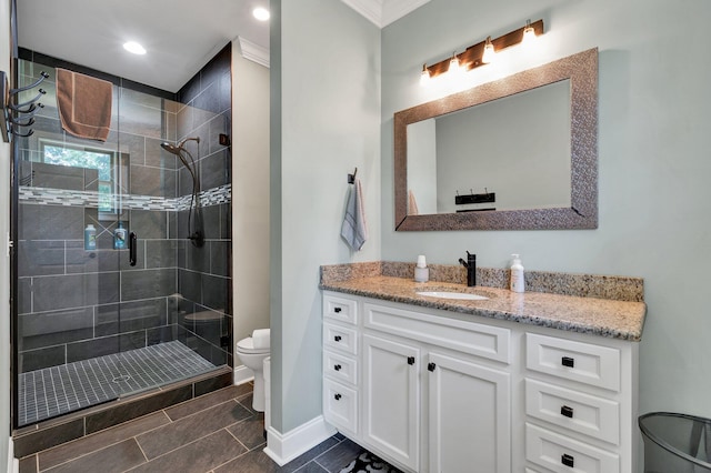 bathroom with tiled shower, vanity, ornamental molding, and toilet