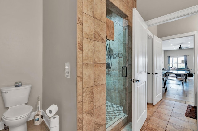 bathroom with ceiling fan, crown molding, tile patterned flooring, toilet, and a shower with shower door