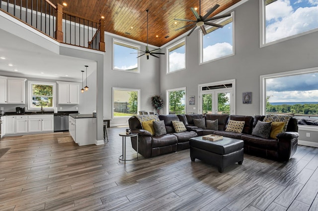 living room with a healthy amount of sunlight, a towering ceiling, and wooden ceiling