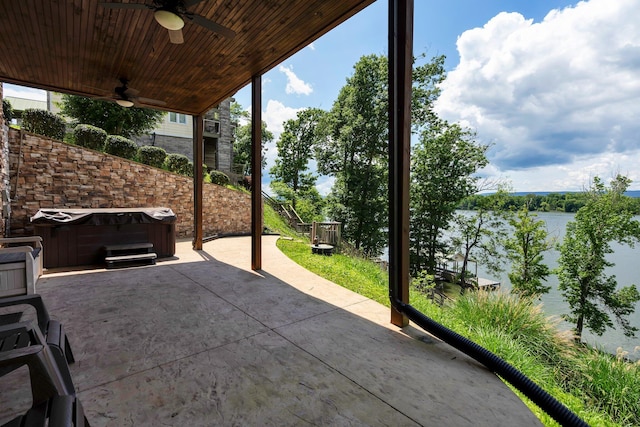 view of patio with ceiling fan, a water view, and a hot tub