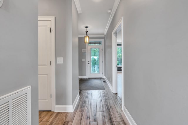 doorway to outside with ornamental molding and light wood-type flooring