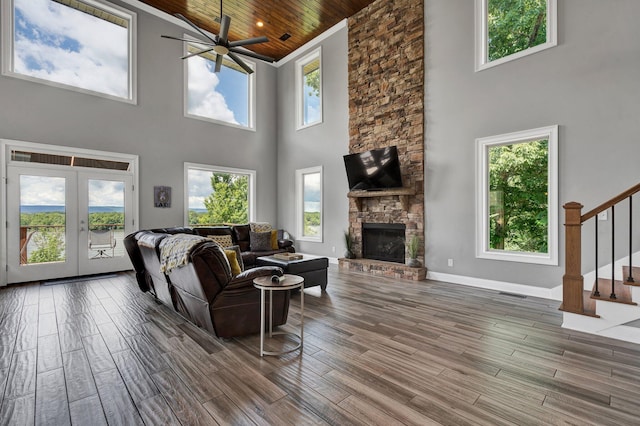 living room with a fireplace, a towering ceiling, a wealth of natural light, and wooden ceiling