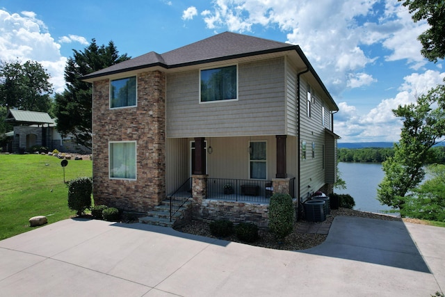 back of property with covered porch, a yard, and a water view