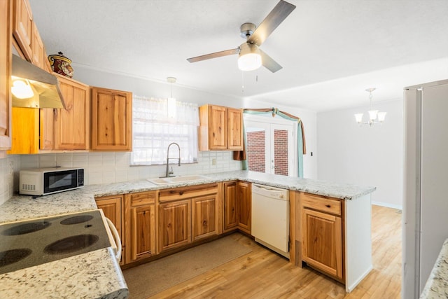 kitchen featuring tasteful backsplash, pendant lighting, kitchen peninsula, sink, and white dishwasher