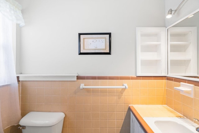 bathroom featuring toilet, tile walls, and vanity