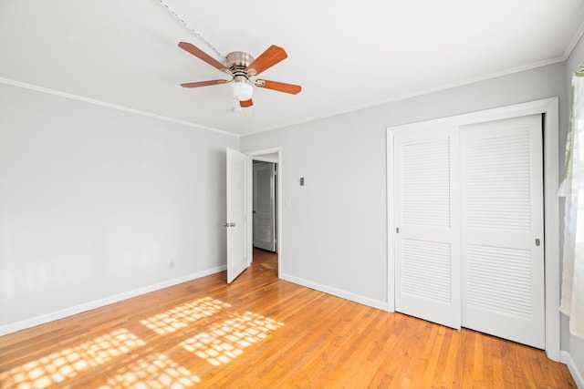 unfurnished bedroom with ceiling fan, hardwood / wood-style floors, a closet, and crown molding