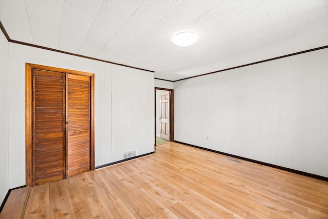 unfurnished bedroom with a closet, ornamental molding, and light hardwood / wood-style floors