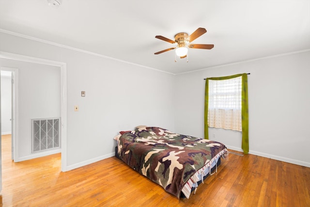 bedroom with ceiling fan, ornamental molding, and hardwood / wood-style flooring