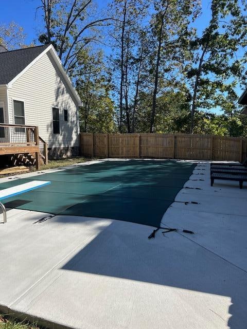 view of pool with a wooden deck, a diving board, and a patio area