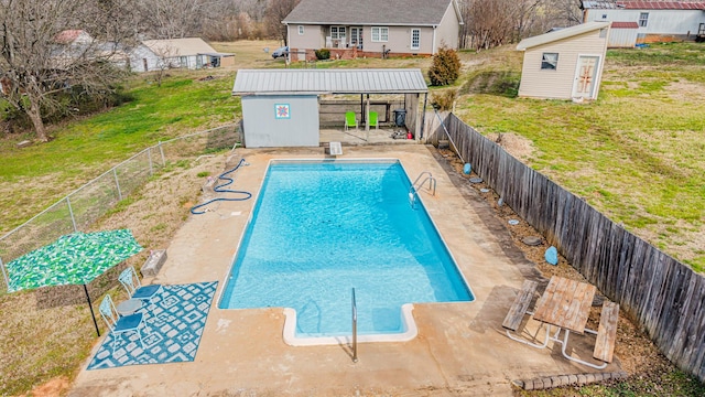 view of pool with an outbuilding, a fenced backyard, a diving board, a yard, and a storage unit