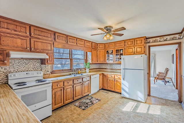 kitchen featuring white appliances, decorative backsplash, a ceiling fan, under cabinet range hood, and a sink