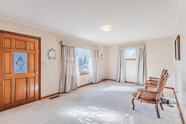 carpeted foyer featuring visible vents and baseboards