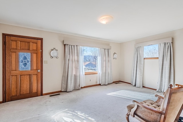 foyer featuring baseboards, visible vents, and carpet flooring