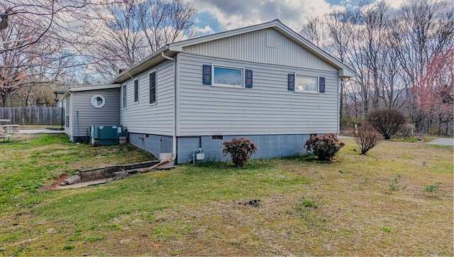 view of home's exterior with a lawn, central AC unit, and fence