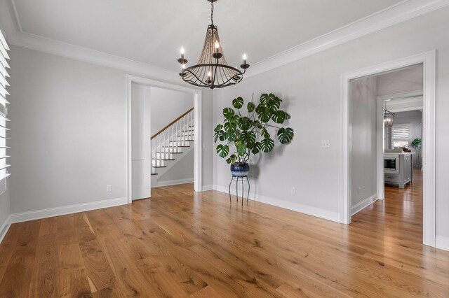 spare room with a chandelier, crown molding, and wood-type flooring