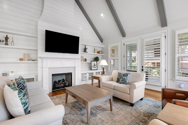 living room with beam ceiling, built in features, high vaulted ceiling, and light wood-type flooring