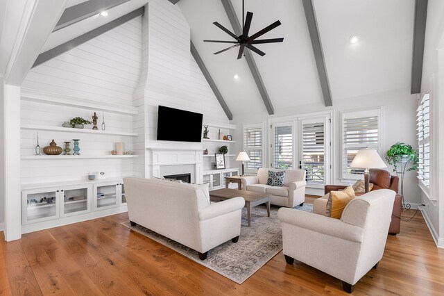 living room featuring beamed ceiling, wood-type flooring, high vaulted ceiling, and ceiling fan