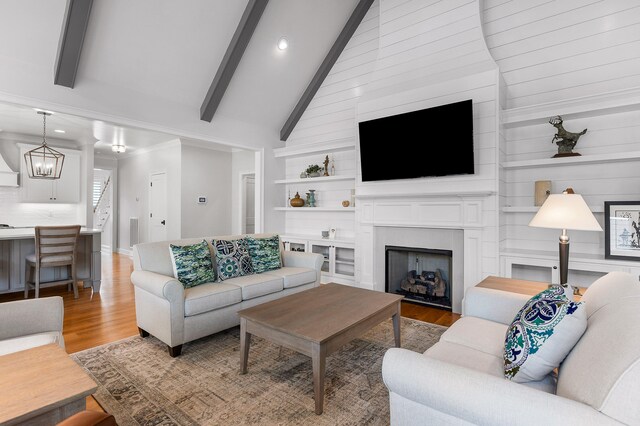 living room featuring beamed ceiling, a chandelier, high vaulted ceiling, and light hardwood / wood-style flooring