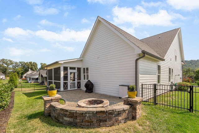 back of house with a fire pit, a sunroom, a patio area, and a lawn